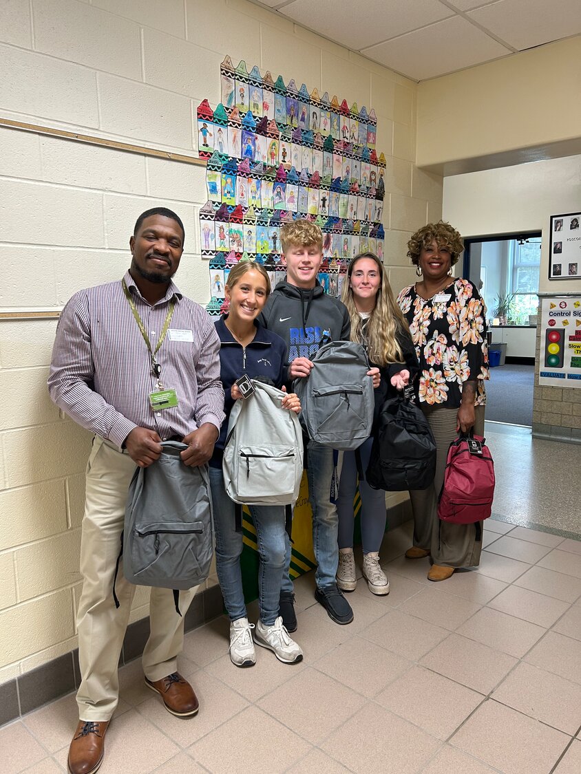 Giving backpacks to students in Roscoe. Pictured are NYSEG’s Uthman Aziz, left; Roscoe Central School students; and ATI’s Children and Family Services Program Manager Akilah Sutphin. They are holding just five of the hundreds of backpacks distributed to students during the project.